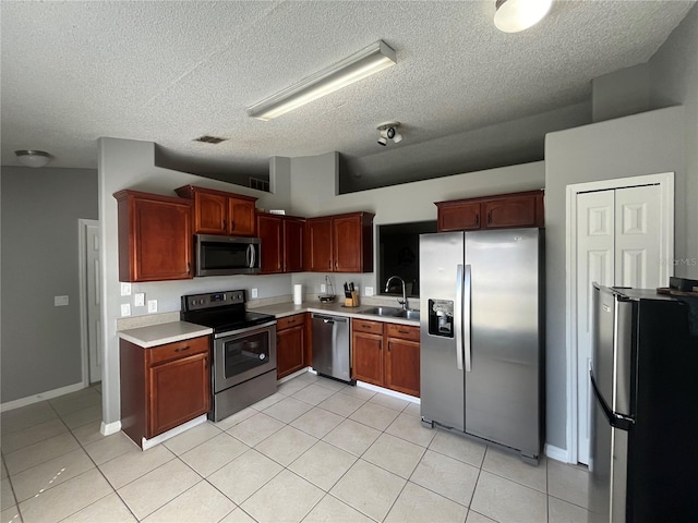 kitchen featuring a textured ceiling, stainless steel appliances, and sink