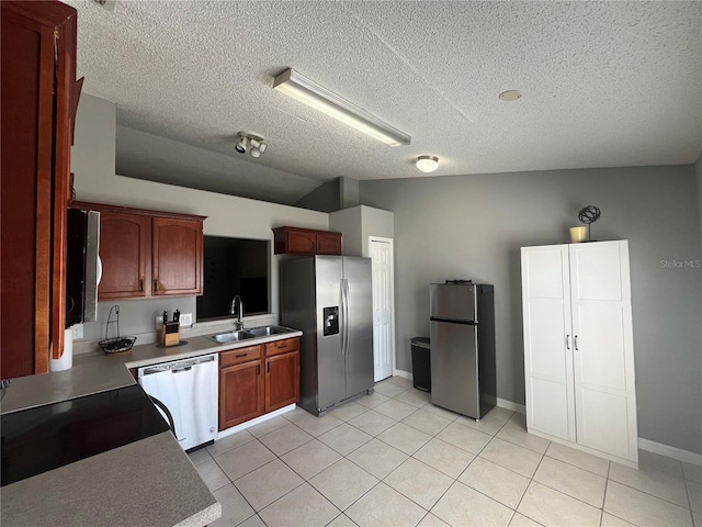 kitchen featuring vaulted ceiling, sink, stainless steel appliances, and a textured ceiling