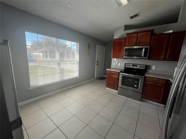 kitchen featuring light tile patterned floors, a textured ceiling, and appliances with stainless steel finishes