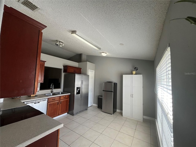 kitchen featuring stainless steel fridge, sink, dishwasher, and a textured ceiling