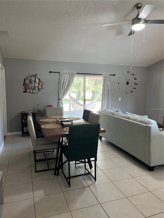 dining area featuring ceiling fan, light tile patterned flooring, and a textured ceiling