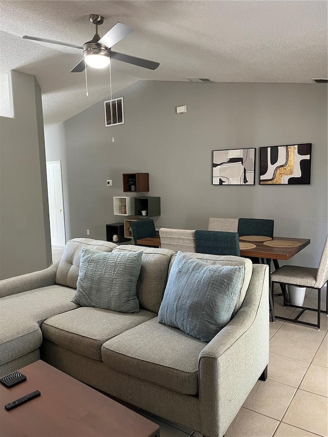 living room with ceiling fan, light tile patterned flooring, lofted ceiling, and a textured ceiling