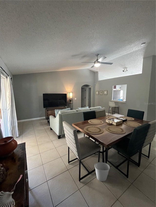 dining space featuring light tile patterned floors, a textured ceiling, vaulted ceiling, and ceiling fan