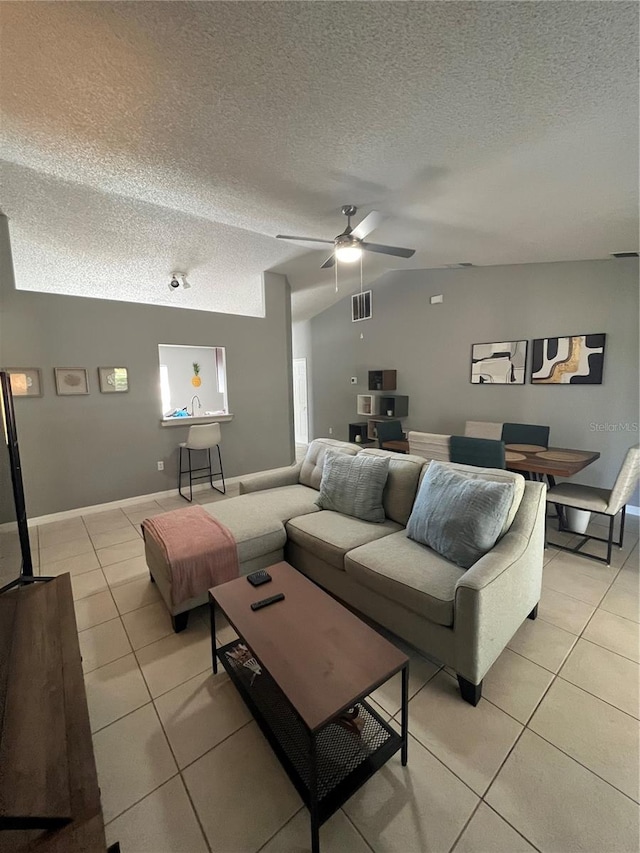 tiled living room featuring ceiling fan, a textured ceiling, and vaulted ceiling