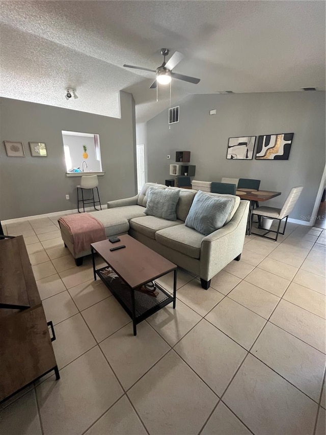 tiled living room featuring a textured ceiling, ceiling fan, and lofted ceiling