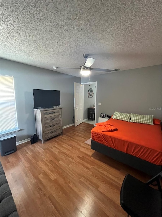 bedroom with ceiling fan, wood-type flooring, and a textured ceiling