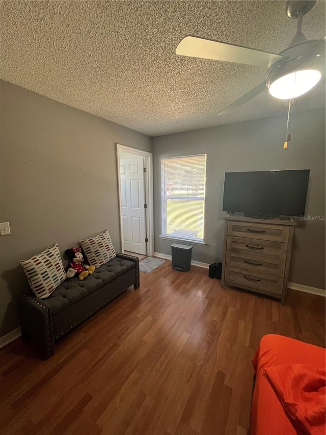 living room featuring ceiling fan, hardwood / wood-style floors, and a textured ceiling