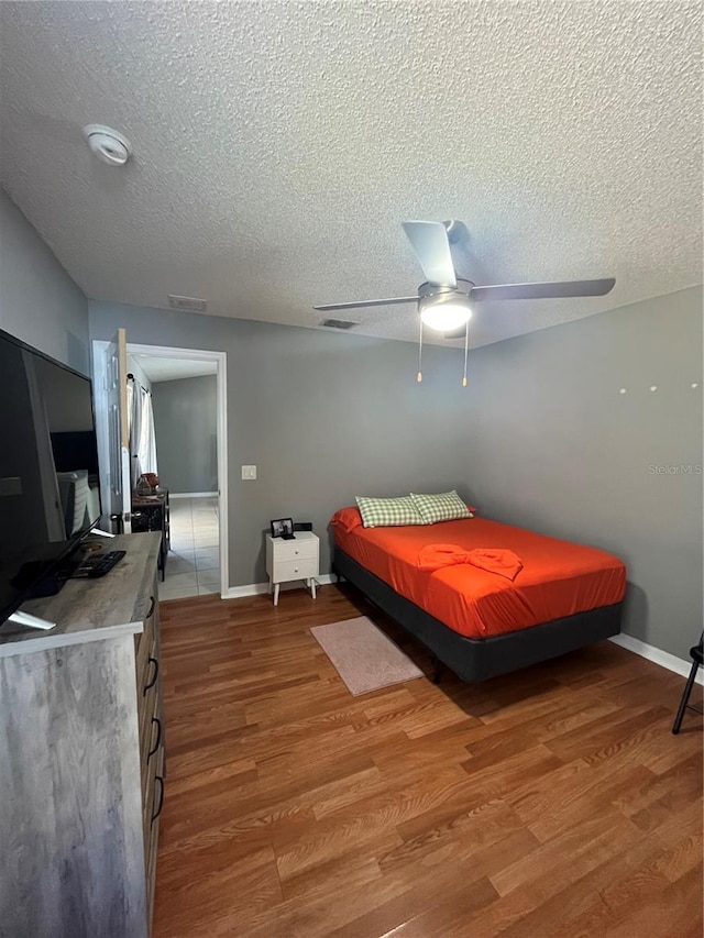 bedroom featuring ceiling fan, wood-type flooring, and a textured ceiling