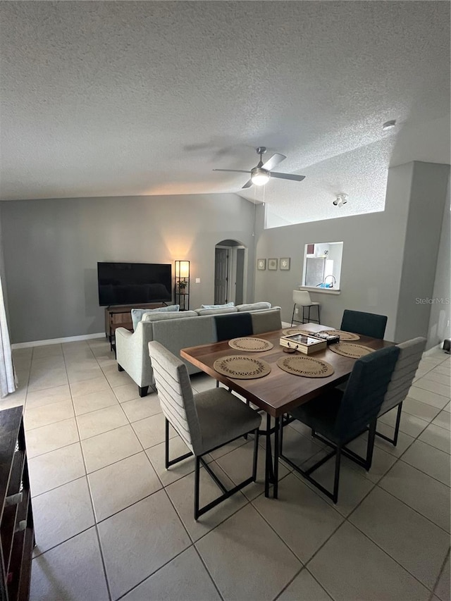 dining area with ceiling fan, light tile patterned flooring, lofted ceiling, and a textured ceiling