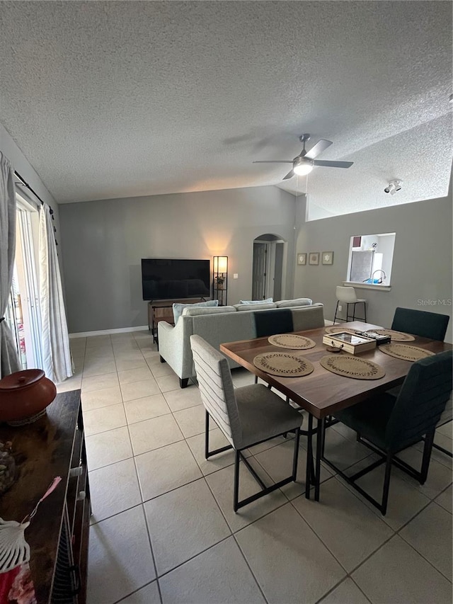 dining room featuring a textured ceiling, ceiling fan, lofted ceiling, and light tile patterned flooring