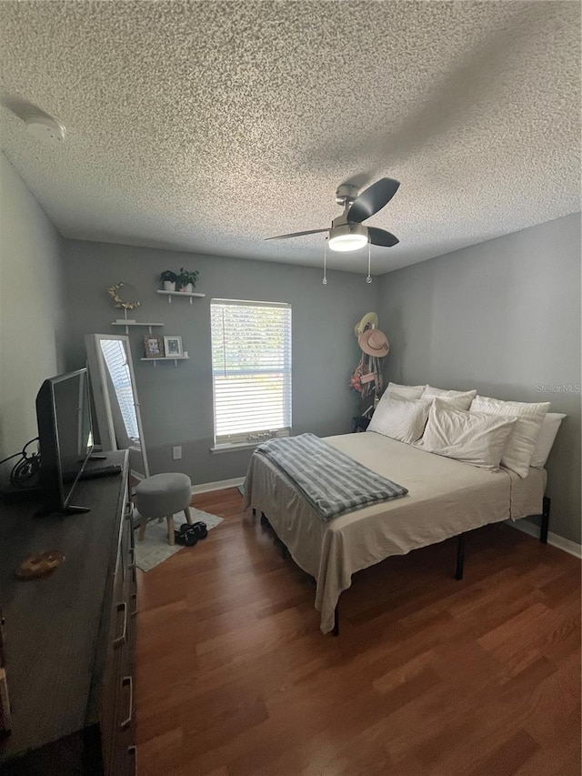 bedroom with ceiling fan, dark hardwood / wood-style flooring, and a textured ceiling