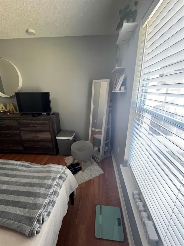 bedroom with a textured ceiling and dark hardwood / wood-style floors