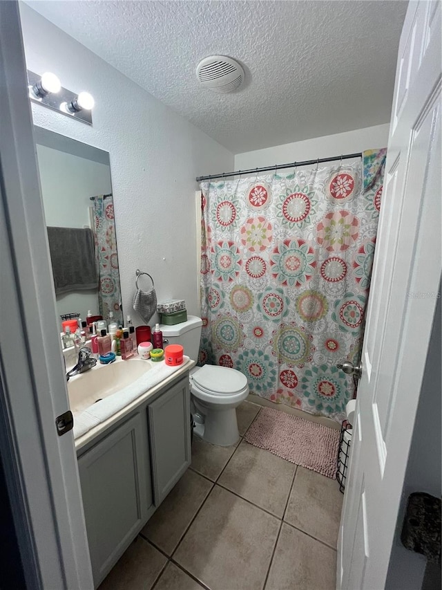 bathroom featuring tile patterned floors, vanity, a textured ceiling, and toilet