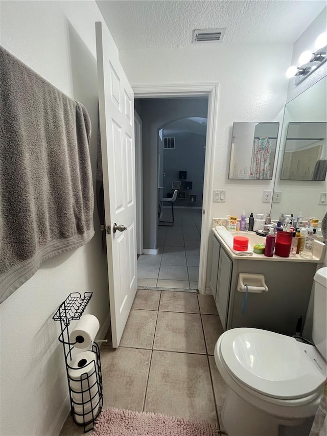 bathroom with tile patterned flooring, vanity, a textured ceiling, and toilet