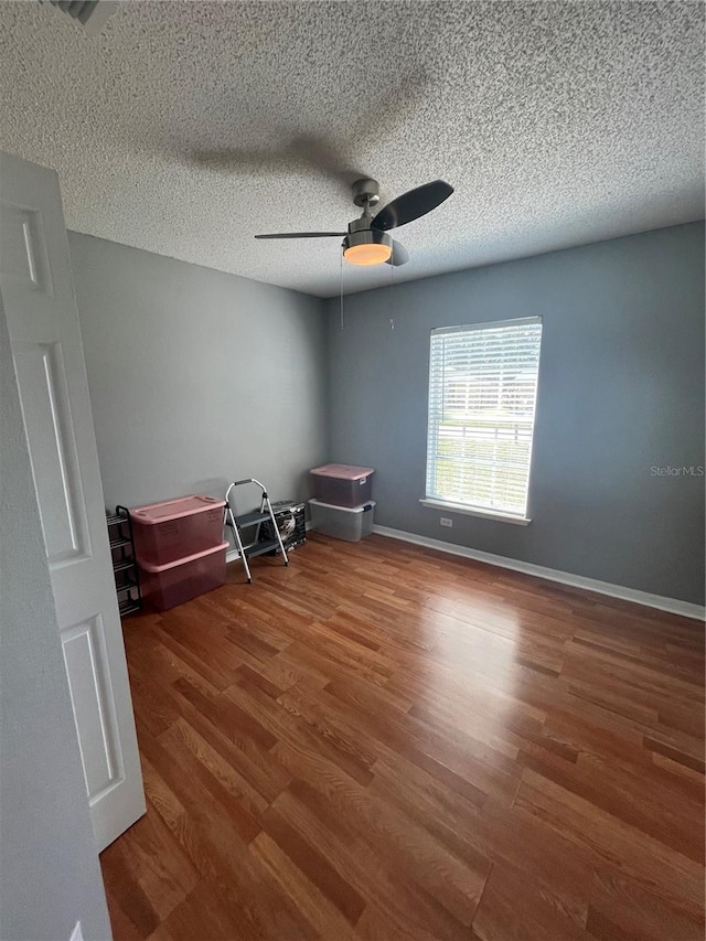 interior space with ceiling fan, wood-type flooring, and a textured ceiling