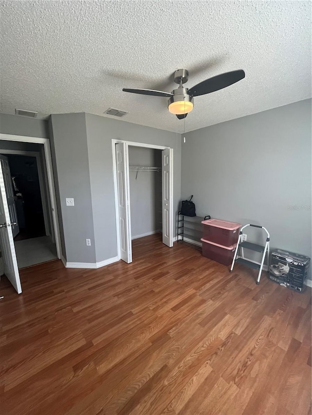 unfurnished bedroom with hardwood / wood-style floors, a textured ceiling, a closet, and ceiling fan