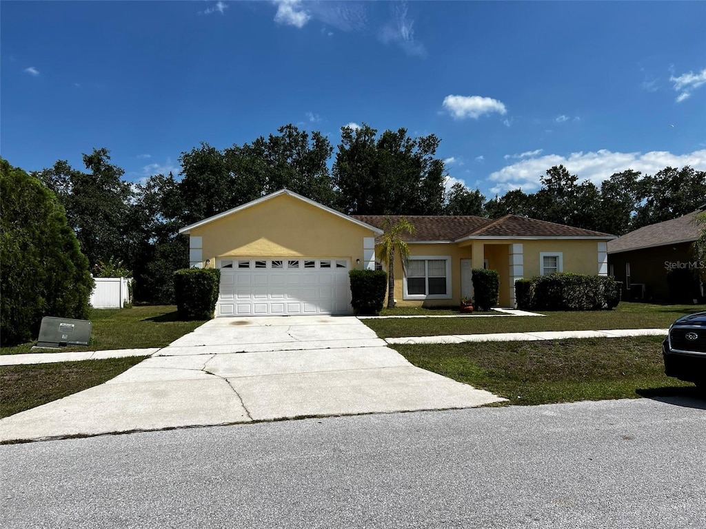 single story home with a garage and a front lawn