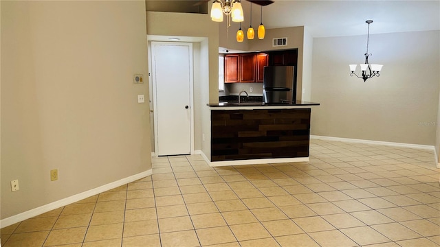 kitchen featuring kitchen peninsula, decorative light fixtures, stainless steel refrigerator, and light tile patterned flooring