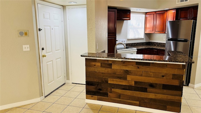 kitchen featuring light tile patterned flooring, dark stone countertops, kitchen peninsula, and white electric stove