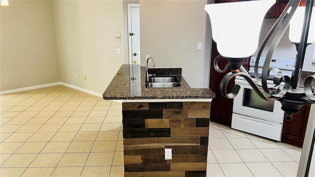 kitchen featuring white stove, kitchen peninsula, light tile patterned floors, and sink