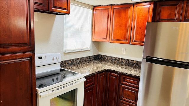 kitchen featuring dark stone countertops, stainless steel fridge, and white electric stove