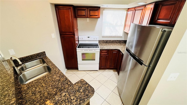 kitchen featuring stainless steel fridge, dark stone counters, sink, electric stove, and light tile patterned floors