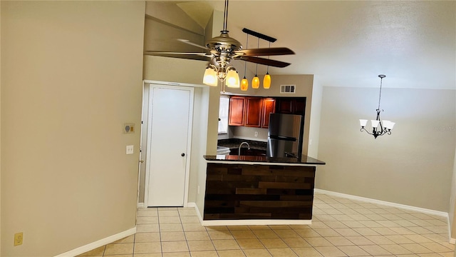 kitchen with lofted ceiling, ceiling fan with notable chandelier, light tile patterned floors, decorative light fixtures, and stainless steel refrigerator