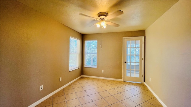 tiled empty room with ceiling fan and a textured ceiling