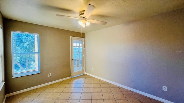 empty room with ceiling fan and light tile patterned floors