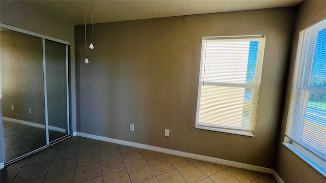 unfurnished bedroom featuring tile patterned flooring, a closet, and multiple windows