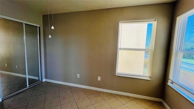 unfurnished bedroom with tile patterned floors, multiple windows, and a closet