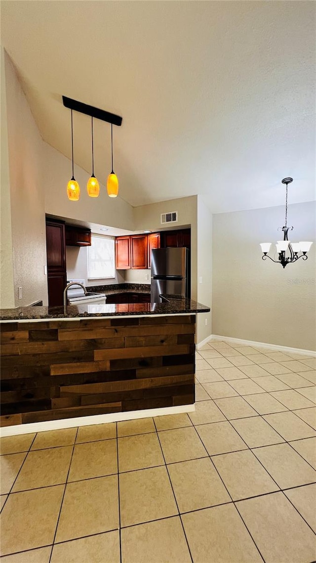 kitchen with stainless steel refrigerator, a chandelier, pendant lighting, and lofted ceiling