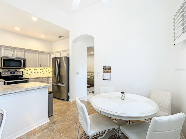 kitchen featuring backsplash, gray cabinetry, light tile patterned floors, and stainless steel appliances