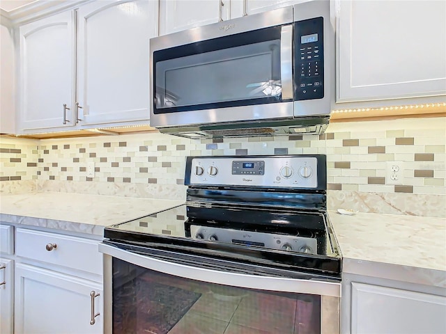 kitchen featuring light stone counters, white cabinetry, backsplash, and appliances with stainless steel finishes