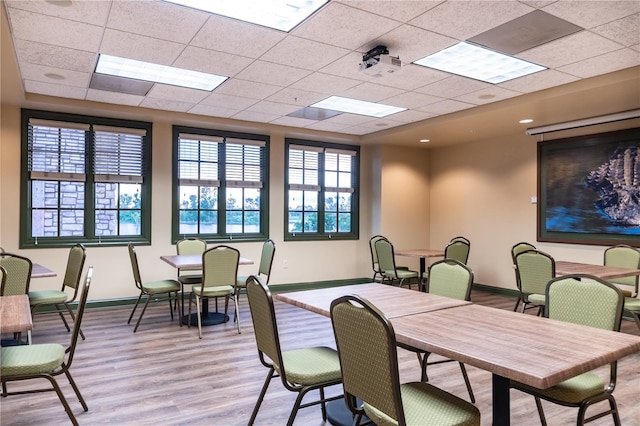 dining space featuring a drop ceiling and light hardwood / wood-style floors