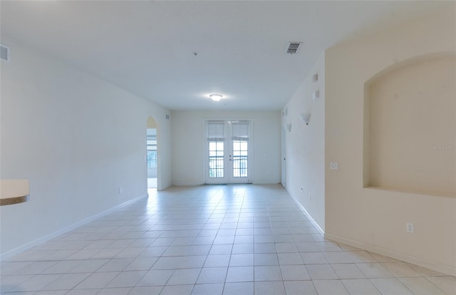 empty room featuring french doors and light tile patterned flooring