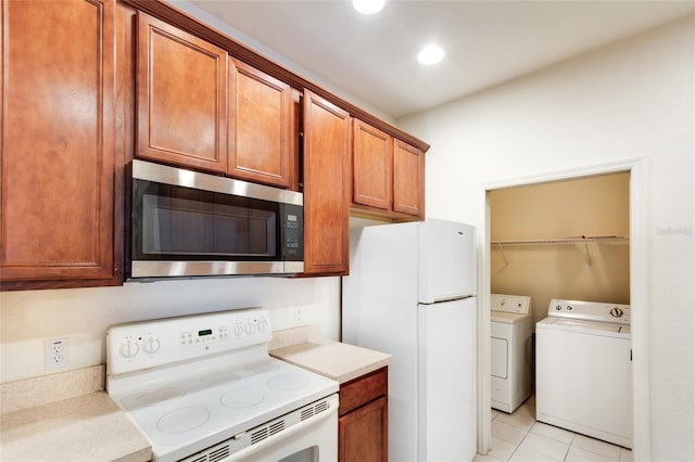 kitchen with light tile patterned floors, washer and dryer, and white appliances