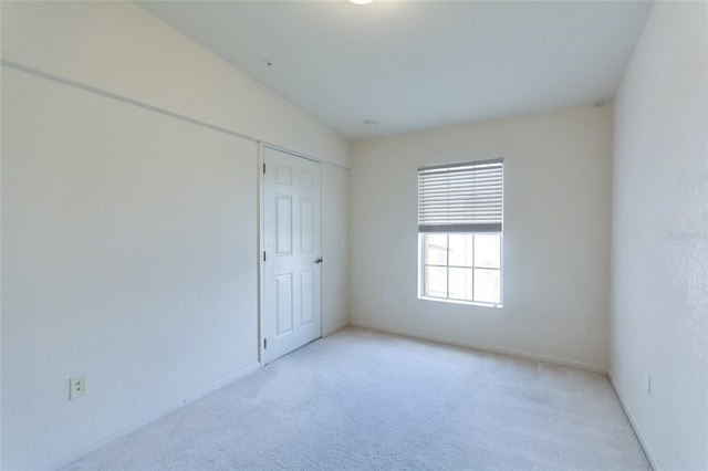 carpeted empty room featuring vaulted ceiling