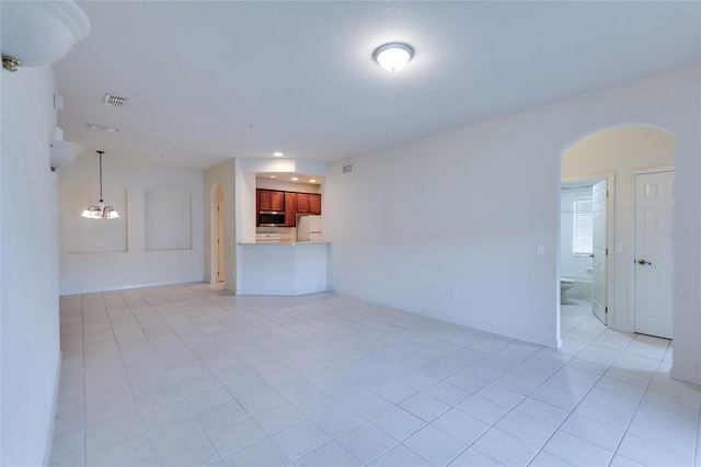 unfurnished living room with a chandelier and light tile patterned floors