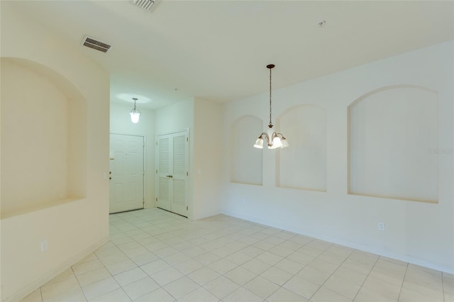 tiled spare room featuring a notable chandelier