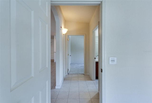 hallway featuring vaulted ceiling and light tile patterned flooring