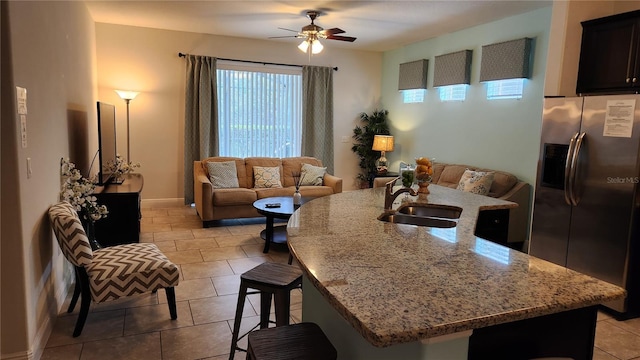 tiled living room featuring ceiling fan and sink