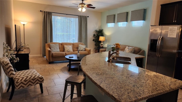 tiled living room with ceiling fan and sink