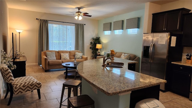 kitchen with a kitchen breakfast bar, an island with sink, ceiling fan, and sink