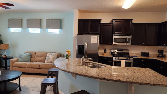 kitchen featuring a healthy amount of sunlight, a kitchen bar, sink, and appliances with stainless steel finishes