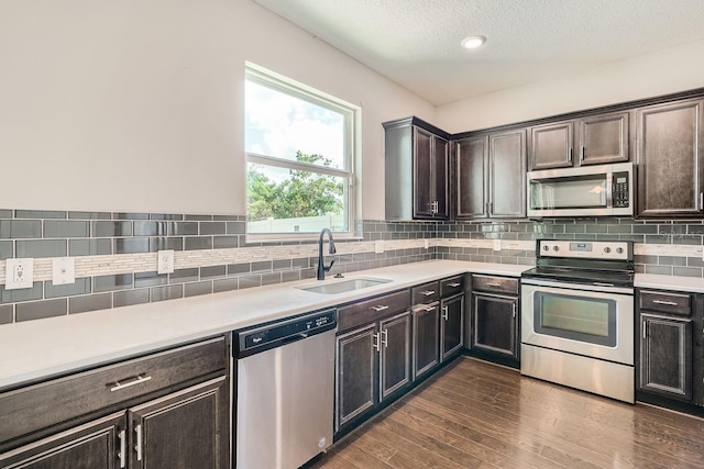 kitchen featuring backsplash, sink, a textured ceiling, appliances with stainless steel finishes, and dark hardwood / wood-style flooring