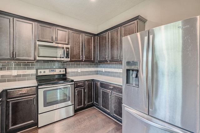 kitchen with tasteful backsplash, light hardwood / wood-style flooring, a textured ceiling, dark brown cabinets, and appliances with stainless steel finishes