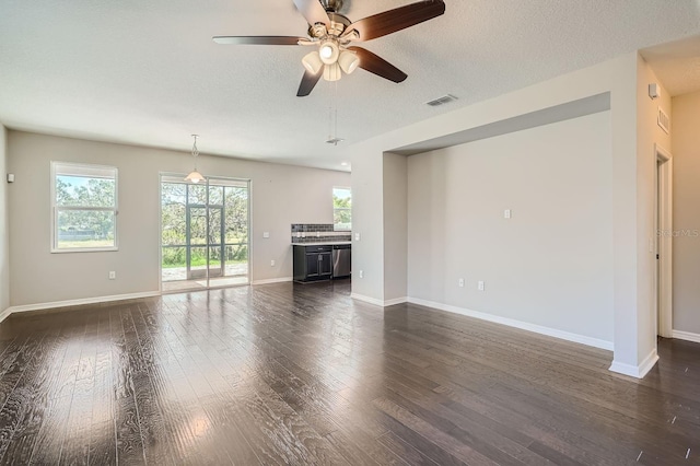 unfurnished living room featuring ceiling fan, dark hardwood / wood-style flooring, and a textured ceiling