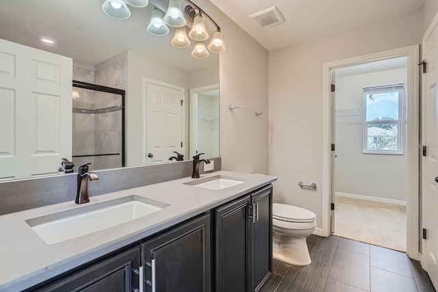 bathroom featuring tile patterned flooring, vanity, toilet, and a shower with shower door