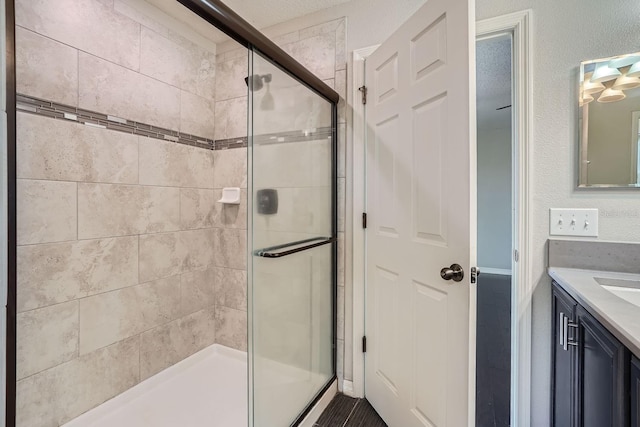 bathroom featuring a textured ceiling, vanity, and a shower with door